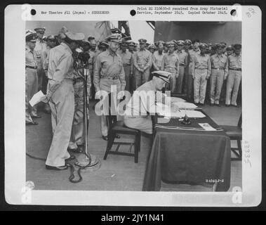 L'ammiraglio della flotta Chester W. Nimitz firma per gli Stati Uniti durante le cerimonie di resa negli Stati Uniti Missouri a Tokyo Bay, 31 agosto 1945. Al microfono a sinistra c'è il generale dell'esercito Douglas Macarthur. Foto Stock