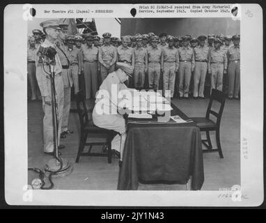 Il generale dell'esercito Douglas Macarthur firma come Comandante supremo alleato durante le cerimonie formali di resa negli U.S.S. Missouri a Tokyo Bay, 31 agosto 1945. Dietro il Gen. Macarthur si trovano il Gen. Jonathan Wainwright (sinistra) che si arrese alla Japanesea Foto Stock