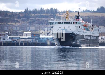 Il traghetto MV Isle of Mull lascia Oban per Craignure in una tranquilla giornata primaverile, con il terminal dei traghetti Oban sullo sfondo. Foto Stock