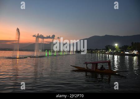 Un barcaiolo ha visto i turisti che fermano lungo il lago dal durante il tramonto a Srinagar. Foto Stock