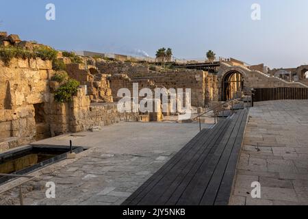 CESAREA, Israele - 2022 agosto, statua dell'imperatore romano che riflette in una piscina, numerosi turisti visitare rovine fortezza costruita da Erode il Grande vicino a Cesare Foto Stock