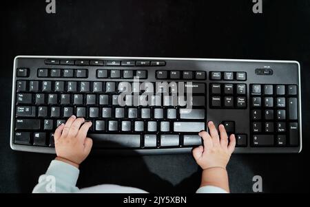 Il bambino ha le mani sulla tastiera del computer. Piccolo uomo d'affari. Esercitarsi a digitare velocemente. Stile di vita familiare Foto Stock
