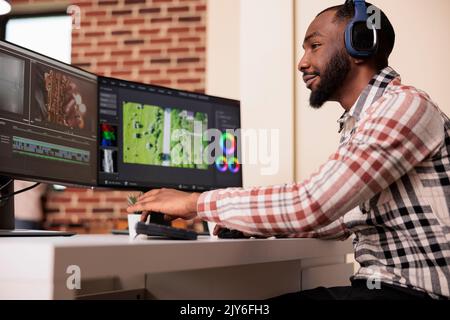 Creator professionale che utilizza un software per modificare filmati su più monitor a casa, modificando filmati con un'applicazione di produzione sul computer. Lavorare sul montaggio su pellicola per creare contenuti multimediali. Foto Stock