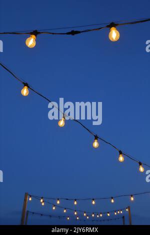 Lampade a corda per esterni contro il cielo blu Foto Stock