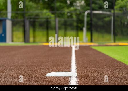 Vista della terza base del campo da softball sintetico del tappeto erboso della scuola superiore guardando verso la piastra di casa. Foto Stock