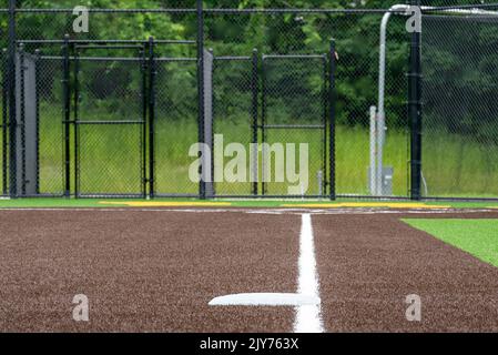 Vista della terza base del campo da softball sintetico del tappeto erboso della scuola superiore guardando verso la piastra di casa. Foto Stock