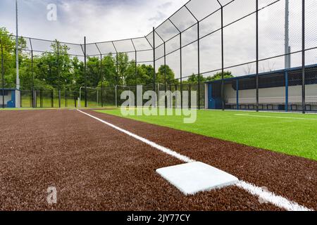 Vista della terza base del campo da softball sintetico del tappeto erboso della scuola superiore guardando verso la piastra di casa. Foto Stock