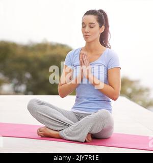 Trovare il suo centro. Foto a tutta lunghezza di una giovane donna che fa yoga all'aperto. Foto Stock