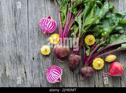 Barbabietole fresche e biologiche crude e pan squash su un tavolo rustico in legno. Foto Stock