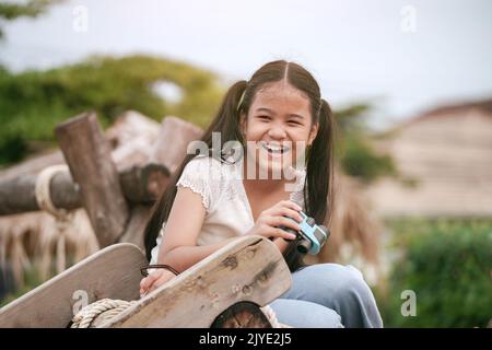 Ragazza felice capretto sta ridendo e tenendo il binocolo nelle sue mani nel parco giochi. Foto Stock