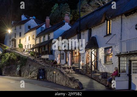 Le persone si godono un drink al di fuori del Rising Sun Inn sul molo di Lynmouth nel Devon settentrionale. Foto Stock