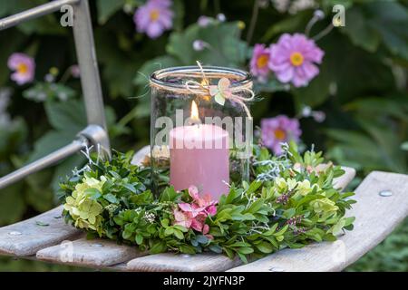 arrangiamento con corona di fiori di ortensia e rami di bosso e candela Foto Stock