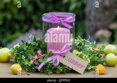 arrangiamento con corona di fiori di ortensia e rami di bosso e candela Foto Stock