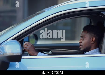 Un serio conducente afro-americano siede in cabina Foto Stock