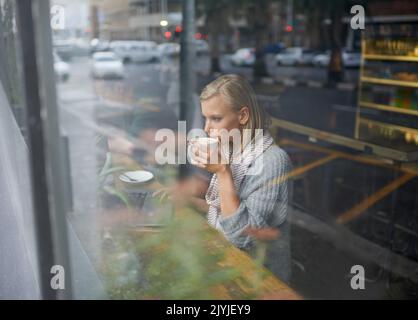 Abbiamo tutti bisogno di un posto per essere soli. Una giovane donna seduta in una caffetteria. Foto Stock