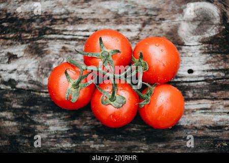 Cinque pomodori freschi rossi su fondo di legno Foto Stock