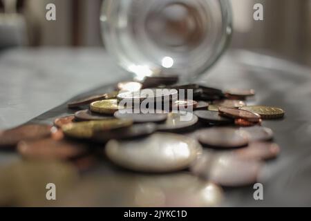 monete in euro che si riversano dal vaso di vetro per pagare le mie fatture Foto Stock