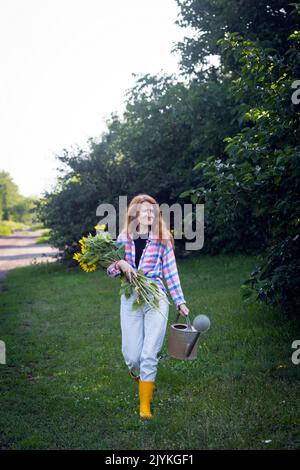 ragazza che tiene un mazzo enorme di girasoli nelle loro mani sullo sfondo di un paesaggio rurale Foto Stock