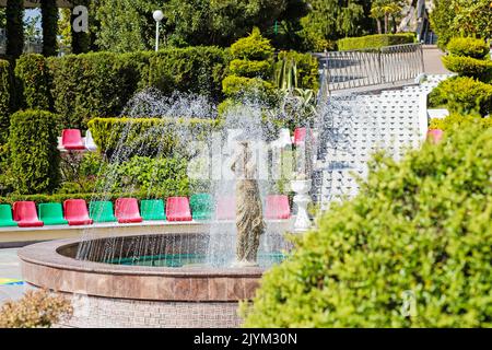 Una fontana si riversa su una statua di una donna. Spruzzi d'acqua e scultura in pietra di una ragazza con caraffa Foto Stock