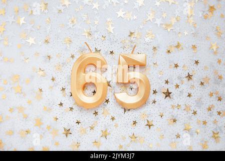 Numero 65 sessantacinque candela d'oro per festeggiare il compleanno su sfondo festivo. Sessantacinque anni di compleanno. Concetto di celebrare il compleanno, l'anniversario, la data importante, la festa Foto Stock