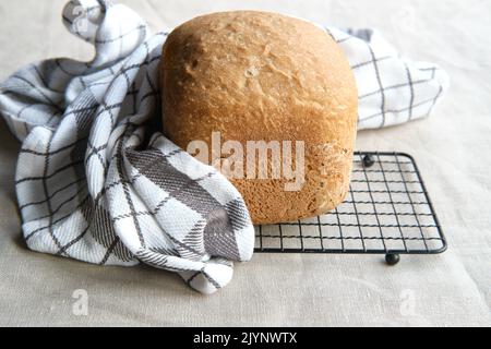 Casa cotto al forno fattoria pane misto. Primo piano su una pagnotta di pane cotta in una macchina da forno. Pane integrale di grano. Rustico biologico casale bio prodotto su essiccazione Foto Stock