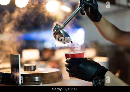 versare il cucchiaio in un bicchiere di vin brulé caldo Foto Stock