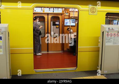 TOKYO, GIAPPONE - 25 agosto 2022: Un treno metropolitano in stile retrò della linea Ginza Tokyo Metro presso una stazione nel centro di Tokyo. Gli sportelli della protezione della piattaforma sono aperti. Foto Stock