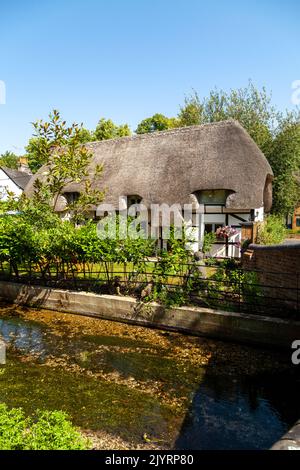 Un cottage dal tetto di paglia lungo un piccolo fiume a Nether Wallop, Hampshire Foto Stock