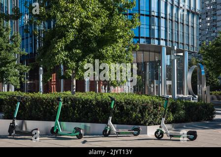Scooter elettrici sullo sfondo dell'ingresso dell'edificio degli affari. Foto Stock