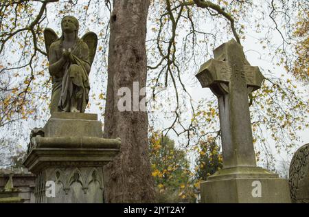 Sculture in pietra vittoriane in una giornata grigia d'inverno nel cimitero di Kensal Green a Londra, Regno Unito Foto Stock