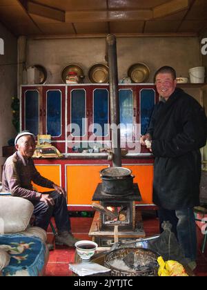 Gli uomini di una famiglia etnica tibetana preparano cibo, cucina e mangiare noodle pasto preparato per una visita turistica occidentale in un piccolo villaggio fuori Songpan antica città nella provincia settentrionale di Sichuan, Cina. PRC. (126) Foto Stock