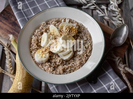 Colazione porridge di cereali con avena, amaranto, quinoa e banane, noci e sciroppo d'acero Foto Stock