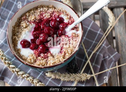 Colazione porridge di cereali con avena, amaranto, quinoa, yogurt e ciliegie cotte Foto Stock