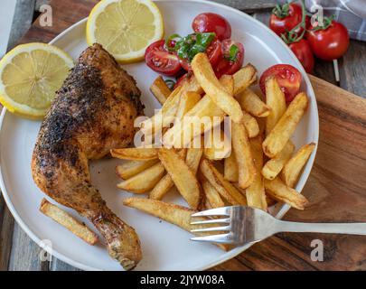 Coscia di pollo croccante con patatine fritte fatte in casa e insalata di pomodoro Foto Stock