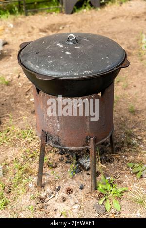 Un calderone per cucinare all'aperto. Tradizioni dell'est. Cucinare pilaf Foto Stock