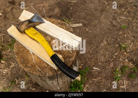 un'ascia con manico in plastica e un tronco di legno spaccato su un moncone Foto Stock