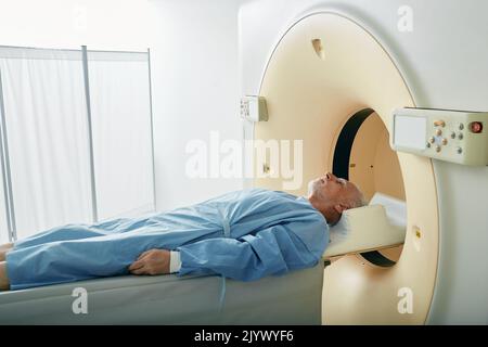 Paziente maturo che entra nello scanner TC durante la tomografia computerizzata nel reparto di radiologia dell'ospedale. Vista laterale Foto Stock