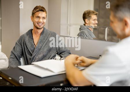 Uomo in accappatoio su appuntamento con terapista senior Foto Stock