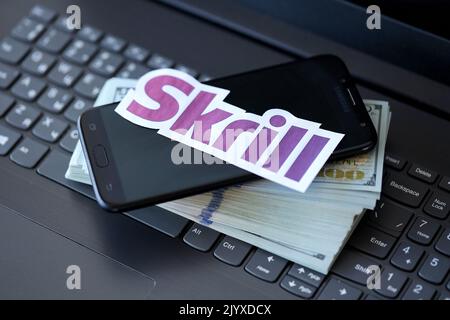 TERNOPIL, UCRAINA - 6 SETTEMBRE 2022 il logotipo di carta Skrill si trova sulla tastiera nera del notebook con banconote in dollari USA. Payoneer è un servizio finanziario americano Foto Stock