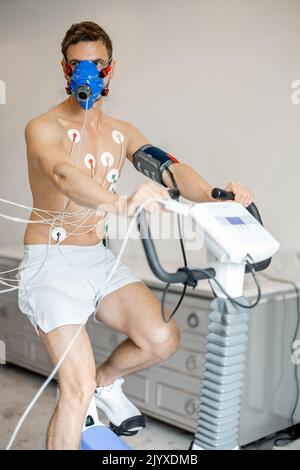 Uomo che esamina il suo sistema cardiovascolare su simulatore di bici Foto Stock