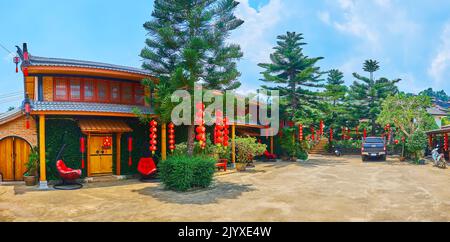 Le piccole case, le lanterne cinesi rosse luminose e le alte e lussureggianti pini dell'Isola di Norfolk nella località di Ban Rak Thai Yunnan, Thailandia Foto Stock