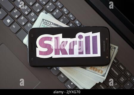 TERNOPIL, UCRAINA - 6 SETTEMBRE 2022 il logotipo di carta Skrill si trova sulla tastiera nera del notebook con banconote in dollari USA. Payoneer è un servizio finanziario americano Foto Stock