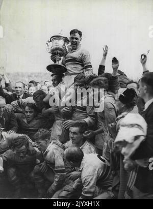 Finale di Rugby League (Maine Road). Frodsham, Warrington, e il capitano di Warrington, reggono con gioia la League Championship Cup, sostenuta dai suoi compagni di squadra, che stanno facendo pressione contro la forza della folla. 8 maggio 1954. Foto Stock