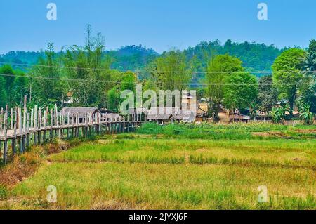 Il vecchio su Tong Pae Bamboo Bridge e tempio buddista, sobborgo di Mae Hong Son, Thailandia Foto Stock