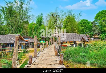 Il villaggio capanne in legno, circondato da addensi di bambù e con su Tong Pae Bamboo Bridge in primo piano, Mae Hong Son sobborgo, Thailandia Foto Stock