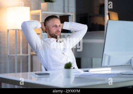 Uomo d'affari seduto in sedia ufficio rilassante vicino al computer Foto Stock