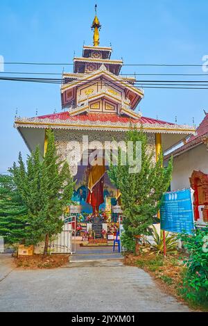 La statua del Buddha in piedi in un piccolo santuario con tetto in pyathat e ombrello hti nel tempio di Wat Pa Kham, Pai, Thailandia Foto Stock