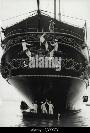 Royal Yacht è vestito per la stagione 1936 - alcuni dei membri dell'equipaggio dipingono e lavano la poppa, mentre la bretella del suo stemma reale è lucidata attraverso le oblò. Nel suo cantiere navale, il Royal Yacht 'Victoria and Albert' sta attraversando un corso completo di refitting e riverniciatura per prepararla alla stagione 1936, a cowes e altrove. Il suo equipaggio è tenuto occupato a pulirla, sia dentro che fuori. Giugno 22, 1936. (Foto per foto stampa associata). Foto Stock