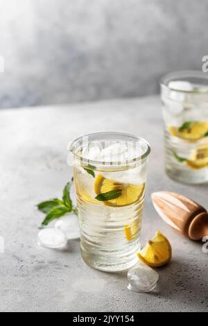 Acqua fredda e rinfrescante disintossicante al limone, menta in bicchieri con spremiagrumi in legno. Limonata fatta in casa o cocktail. Spazio di copia Foto Stock