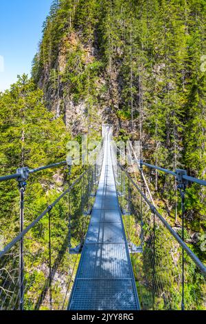 Semplice ponte sospeso sulla valle di montagna Foto Stock